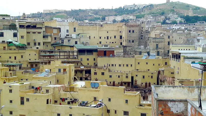 Layers of brown adobe buildings in Fes Medina with camel hides hanging over walls.