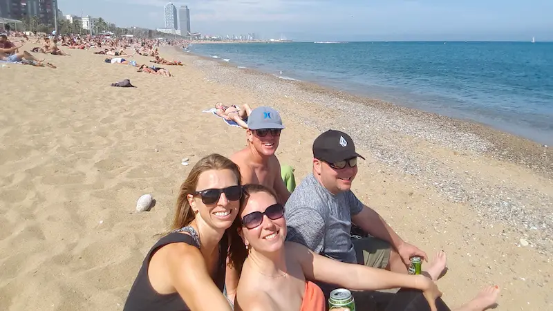 Four friends sitting on a busy beach in Barcelona, Spain.