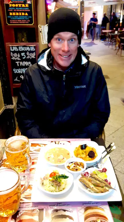 Man with a selection of tapas on the table at night in Seville, Spain.