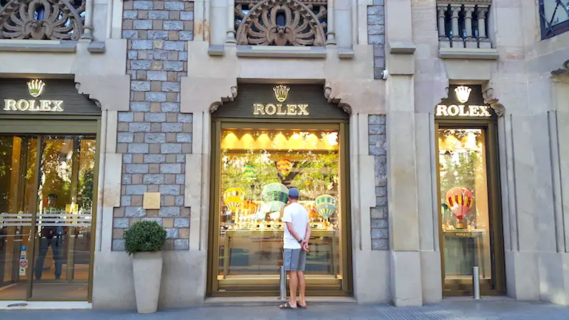 Man looking in the large window of a Rolex store in Barcelona, Spain.