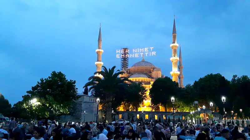 Blue Mosque lit up at sunset with crowds for Ramadan in Istanbul, Turkey.