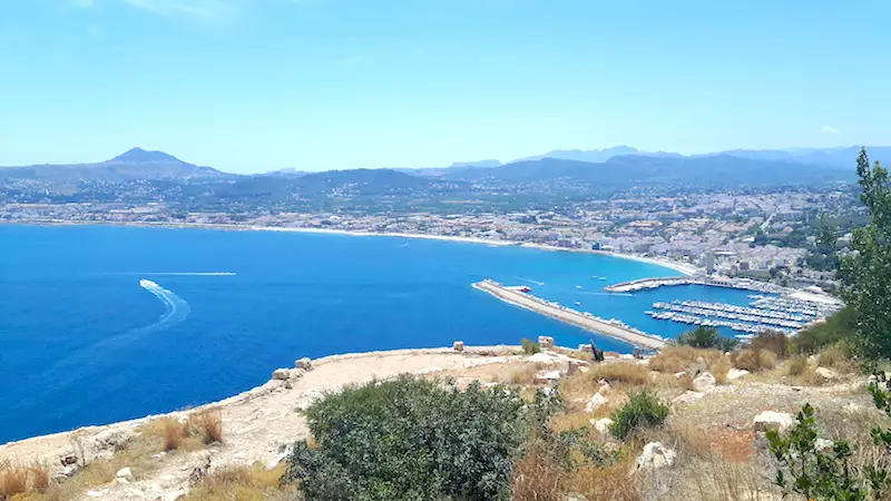 Looking down at Javea harbour with blue water in a long bay in Spain.