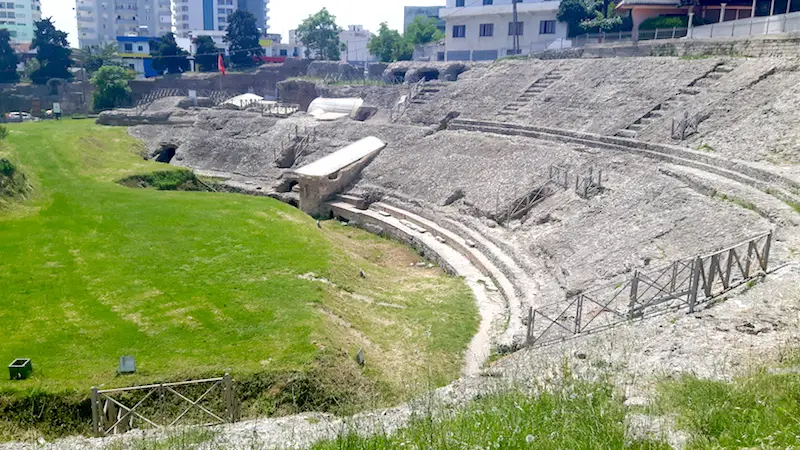 Ancient ruins of a Roman amphitheatre surrounded by modern buildings in Durres, Albania.