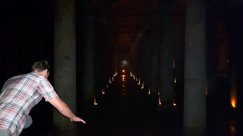 Man leaning over towards the columns in the underground Basilica Cistern in Istanbul, Turkey.