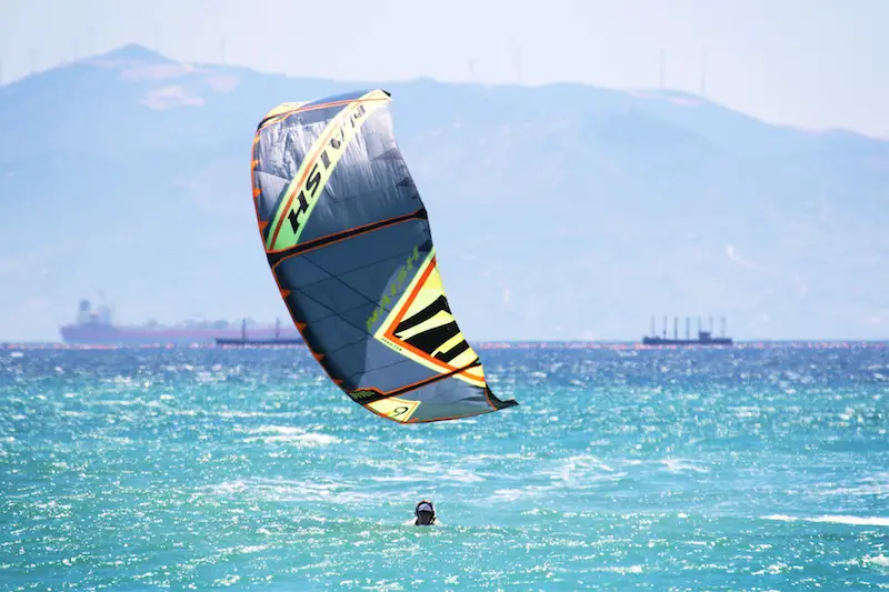 Colourful kite just above the blue water with a head visible in Tarifa, Spain.