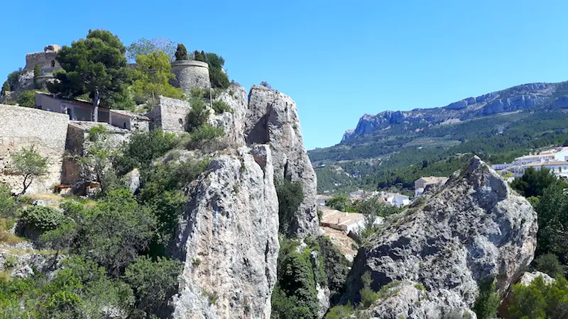 Castle perched on a rocky summit overlooking surrounding landscape in Castell de Guadalest, Spain