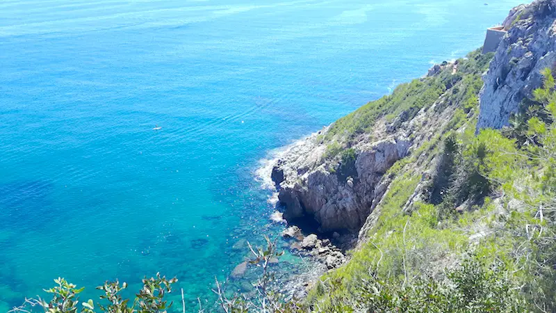 Looking down to clear blue water from cliffs of Montgo, hiking in Denia Spain.