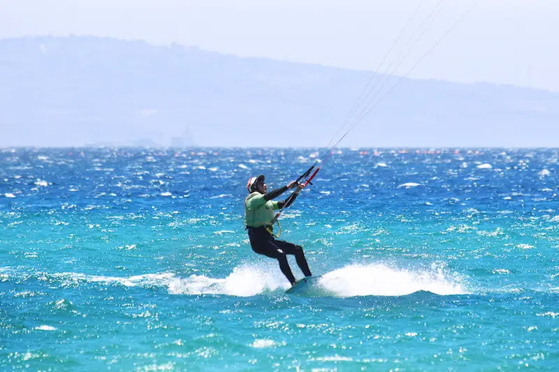 Man kiteboarding in a wetsuit and helmet in Tarifa, Spain.