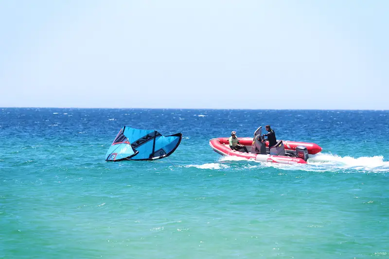 Blue kite in the water and a red rescue dinghy in the blue waters in Tarifa, Spain.