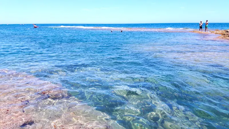 Crystal clear water with people snorkelling in Denia Spain.