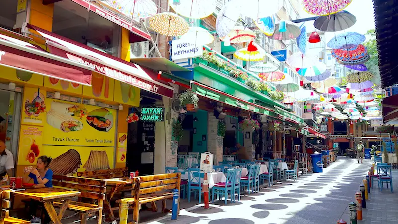 Colourful street filled with outside restaurant tables and covered with a grid of umbrellas in the Asian side of Istanbul, Turkey.