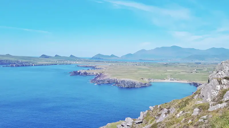 View across the Dingle Peninsula from Clogher Head of rugged green hills and bright blue water on the Dingle Peninsula, Ireland.