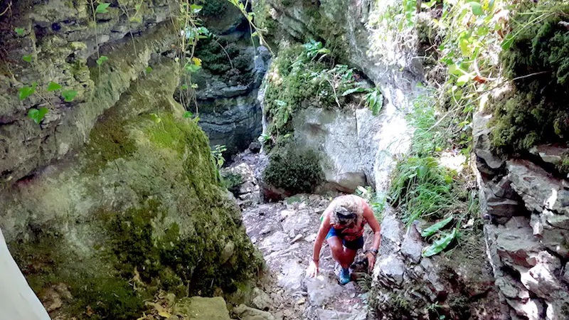 Woman climbing through a narrow gorge called Ebbor Gorge, Wookey Hole UK