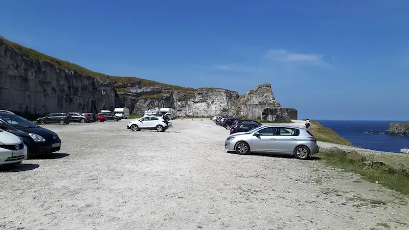 Cars parked in an old quarry along the north coast of Northern Ireland at Carrick-a-Rede rope bridge.