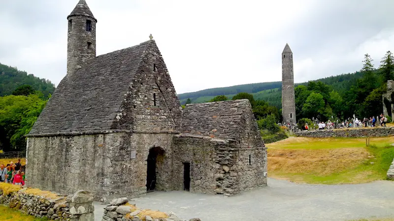 Ancient chapel and tower surrounded by nature in Glendalough Monastic Site, Ireland