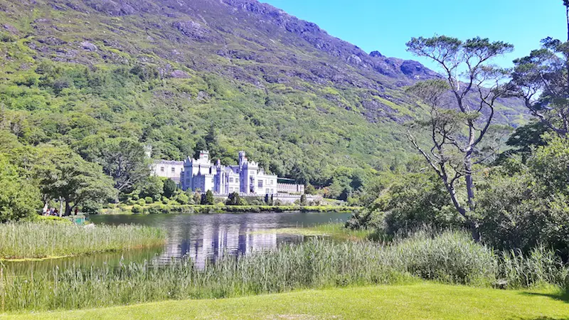 Huge, ornate building of Kylemore Abbey on the edge of a lake in Connemara National Park, Ireland.