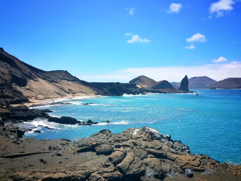 Bright blue waters against dark volcanic rock of Bartolome Island in Galapagos.