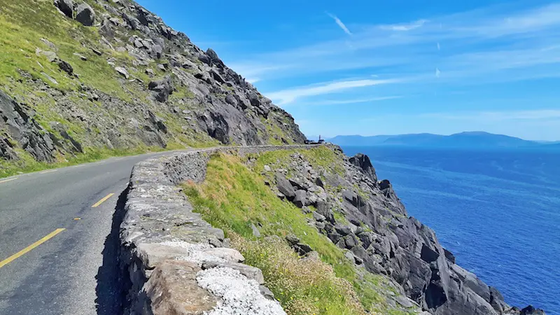 The road winding around a narrow cliff edge on the Slea Head Drive, Dingle Peninsula, Ireland.
