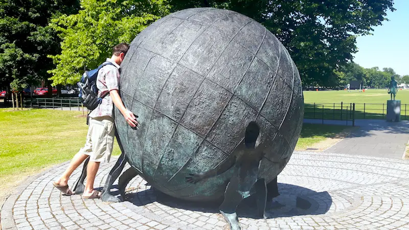 Man looking into a giant metal globe in a park in Armagh, Northern Ireland.