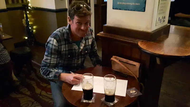 Man taking a pub quiz with Guinness on the table in Conwy, Wales.