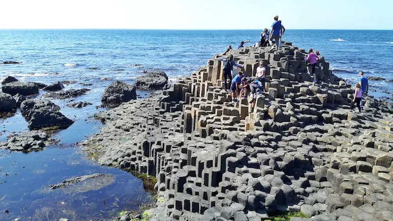 Children climbing the hexagonal shaped rocks of Giant's Causeway, Northern Ireland.