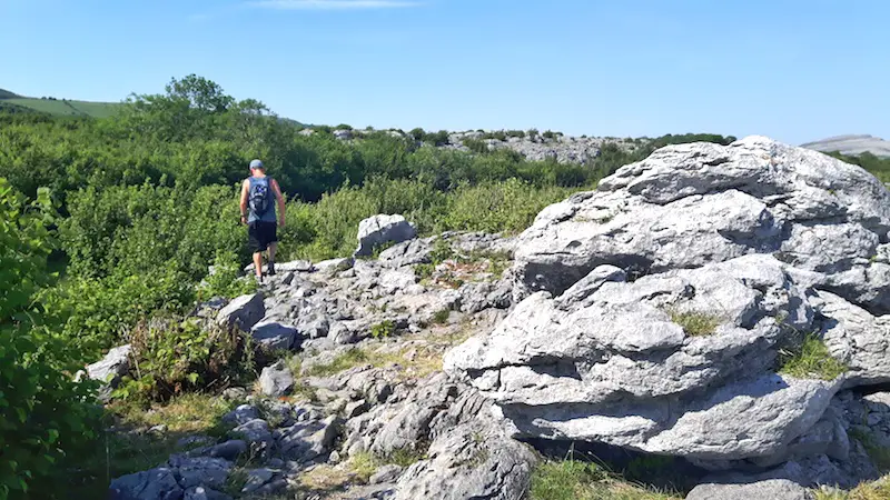 Man hiking across the rocky landscape of The Burren, Ireland.