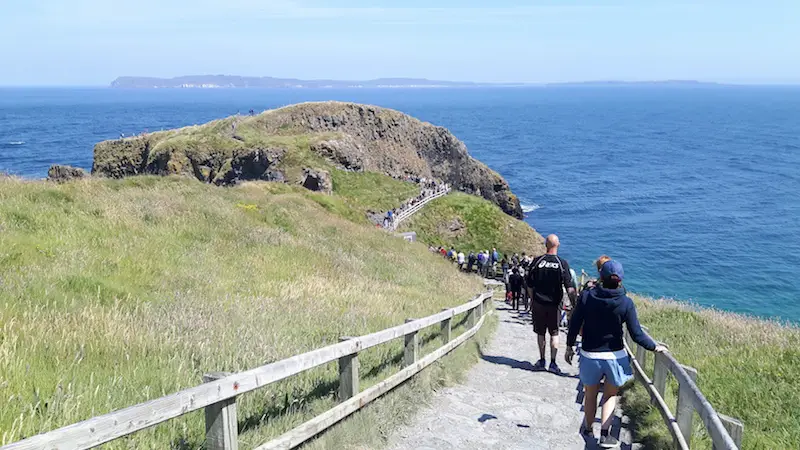 A long line of people waiting to walk across Carrick-a-Rede rope bridge, Northern Ireland.