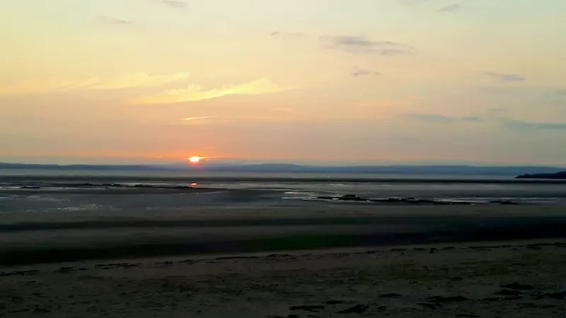 Sunset across a wide bay in Kewstoke, Somerset, UK.