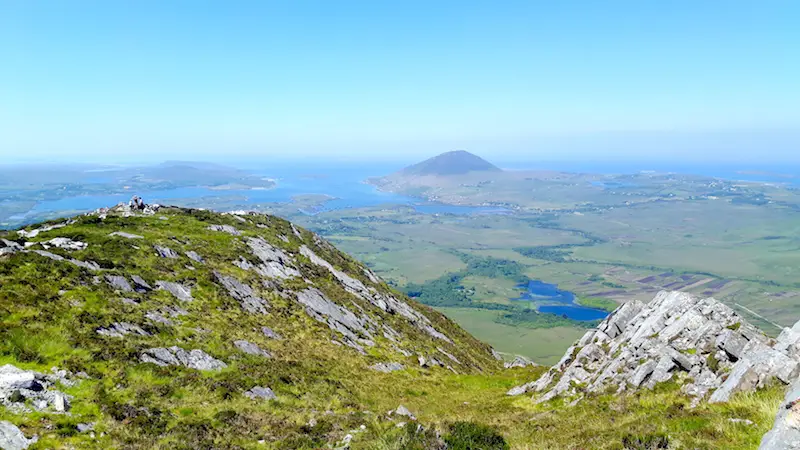 View of green hills and blue Atlantic Ocean from the top of Diamond Hill in Connemara National Park, Ireland.