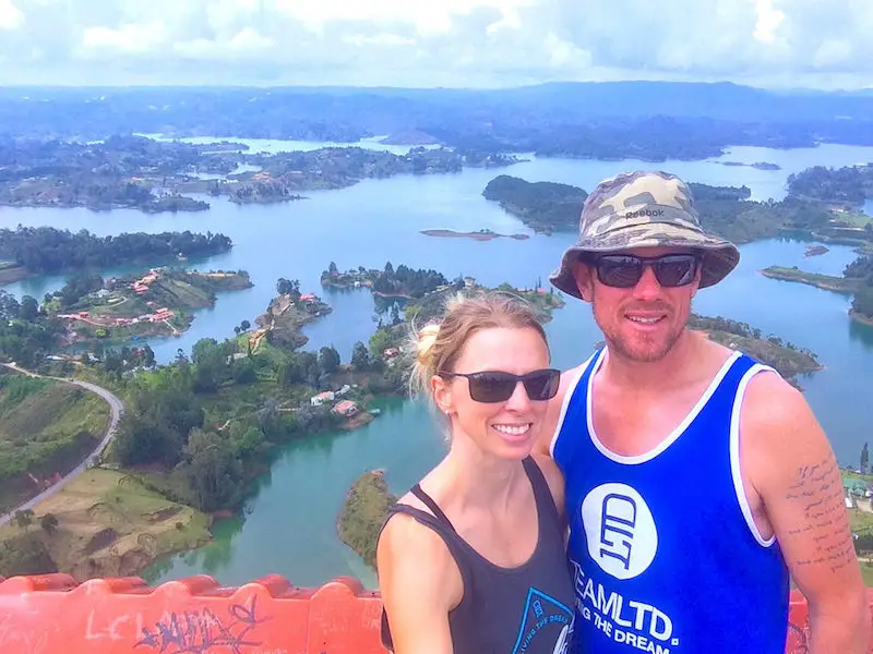 Couple smiling with a view of blue lakes and green islands of Guatape, Colombia.