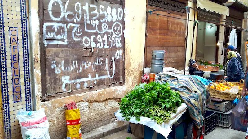 Arabic signs, fresh herbs for sale on a cart in an alleyway in Fes Medina, Morocco.