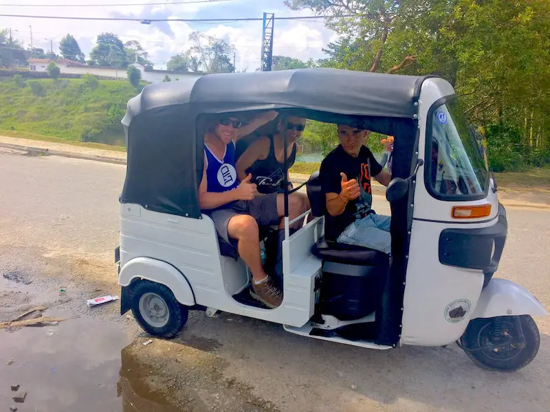 Couple riding in the back of a tuk-tuk, small motorbike taxi, in Guatape, Colombia.