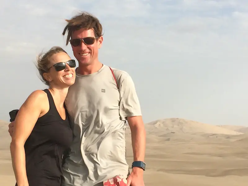 Man and woman smiling in the sand dunes in Huacachina, Peru.