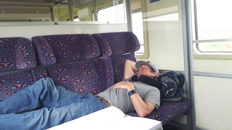 Man laying across three seats sleeping in a train in Morocco.