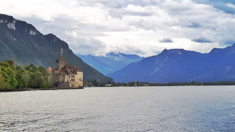 A European style castle on the edge of Lake Geneva with the Alps mountains all around. Chateau Chillon in Montreax, Switzerland.