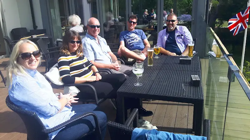 Five adults having a drink on a patio overlooking the River Thames in Maidenhead, UK.