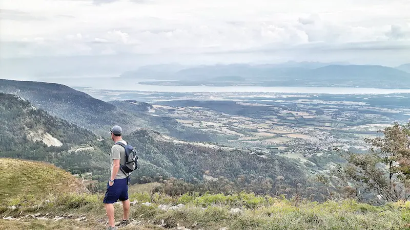 Man looking over the Jura Mountains to the view of the Alps and Lake Geneva, France.