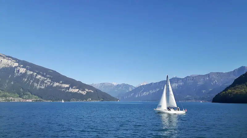 White sails of a yacht in Lake Thun, surrounded by the Swiss Alps, Switzerland.