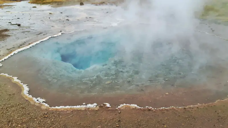 Clear blue water steaming in a geyser on the golden circle in Iceland.