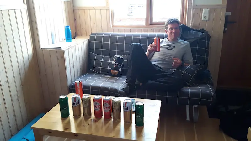 Man sitting on a couch with a row of Icelandic beer cans on the table.