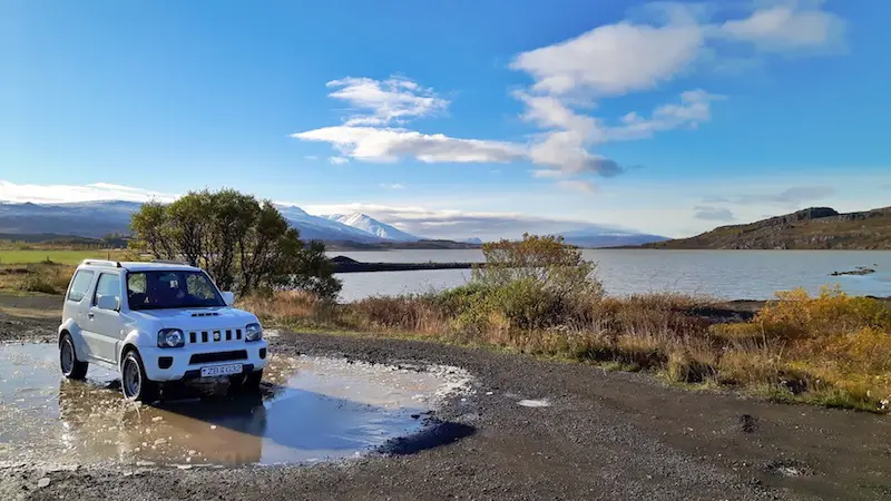 Iceland rental car with lake and snow covered mountains in the background