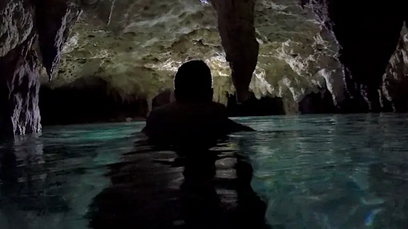 Silhouette of a man in the water in a dark cave cenote in Mexico