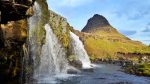 Triple waterfall with a green mountain in a perfect cone shape behind in Iceland.
