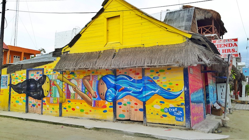 Bright yellow building in main square of Isla Holbox with mural, Mexico.