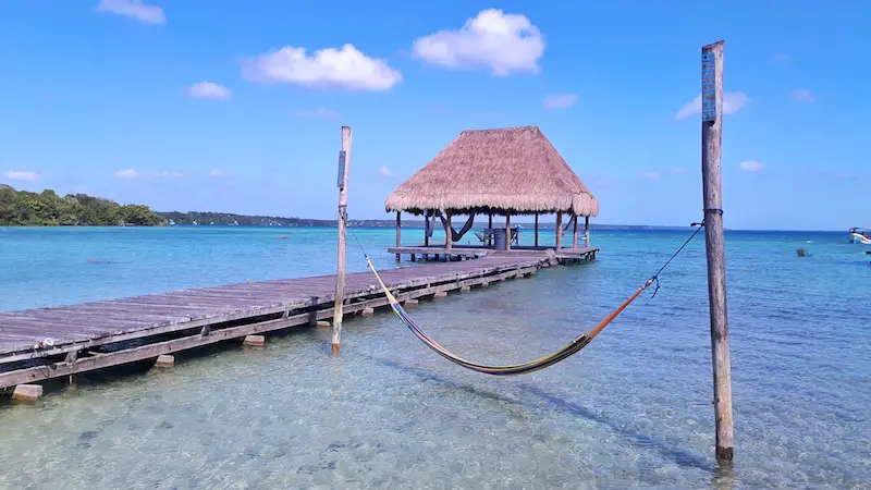 Hammock and palapa over the blue water of Laguna Bacalar in Mexico