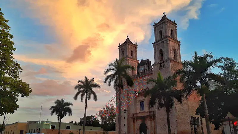 Twin towers of a cathedral with palm trees and bright sunset, Valladolid Mexico