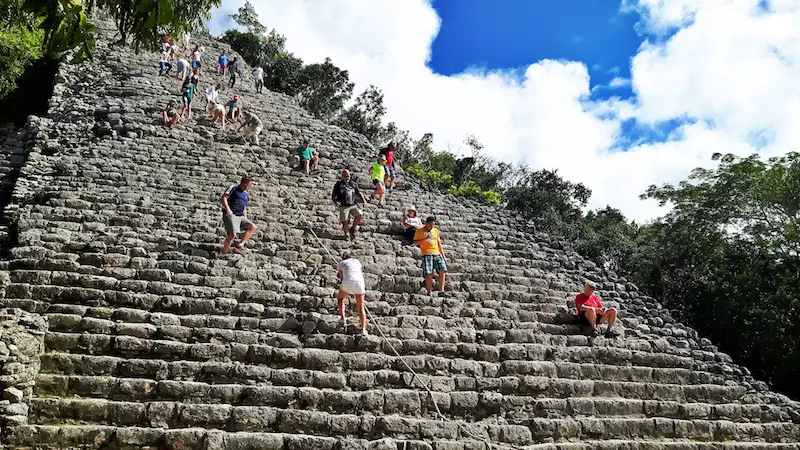 People climbing up and down the tall pyramid at Cobá, Mexico.