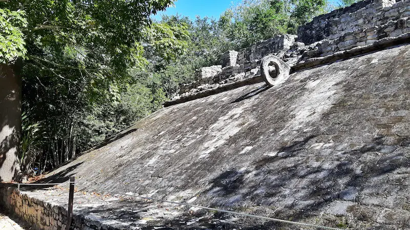 One slanted stone wall with a stone ring near the top in an ancient ball court in Coba ruin, Mexico.