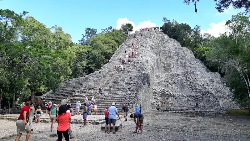 Lots of people around the base of the pyramid while others climb to the top at Coba mayan ruins, Mexico.