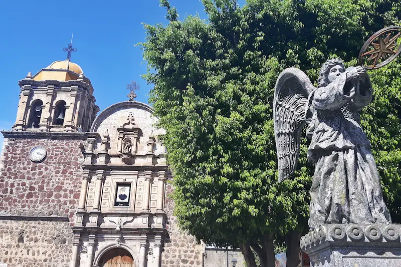 The stone church tower and angel statue in the main plaza of the pueblo magico, Tequila, Mexico.